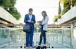 © Cavan Images - Group of smiling business people in a meeting together outdoors.