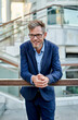 © Cavan Images - caucasian businessman standing in front of a corporate building