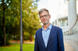 © Cavan Images - caucasian businessman standing in front of a corporate building
