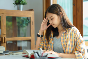 Wall Mural - Education and literacy concept, College student girl feel confused while reading a book in library