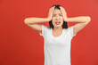 © Johnstocker - Portrait of Attractive shocked young asian woman in white t-shirt standing isolated on red background