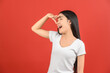 © Johnstocker - Portrait of Excited young asian woman in white t-shirt holding hand above eyes and peering into distance, looking far away isolated on red background