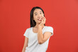 © Johnstocker - Portrait of Happy young asian woman in white t-shirt smiling and looking up isolated on red background