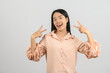 © Johnstocker - Portrait of Happy young asian woman in pink shirt doing peace symbol with fingers isolated on white background