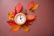 Fall time change still life with colorful tree foliage and wooden frame clock. Fall back concept background. A Clock and fallen leaves composition on brown background.