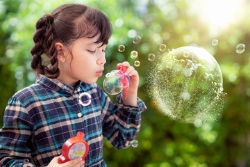 Asian preschool girl play soap bubble by blowing toy in playsgound