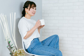 Wall Mural - 部屋でコーヒーを飲みながらリラックスしてくつろぐアジア人女性
