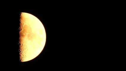 Wall Mural - Timelapse. A glowing golden huge moon as seen from earth through the atmosphere against a starry night sky. A large moon moves across the sky, the moon moving from the left frame to the right.