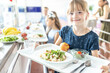 © Westend61 - Smiling girl holding food tray in school cafeteria