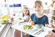 © Westend61 - Smiling girl holding tray at lunch break in school cafeteria