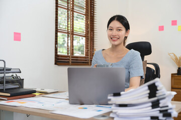 Wall Mural - Portrait accounting asian woman working for financial with paperwork using laptop computer.