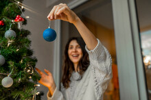 Woman Holding Christmas Ornaments To Decorate Christmas Tree