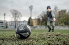 Soccer Ball On Grass With Boy In Background At Sports Field