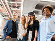 © Westend61 - Happy businesswoman wearing VR goggles standing with colleagues in office