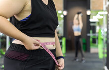 Fat Woman Using Measuring Tape To Measure Waist In Fitness Club, Weightloss And Fitness Concept