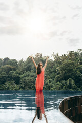 Wall Mural - Woman in infinity pool with her hands raised