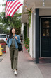 © PR Image Factory - travel lifestyle and people on holiday in usa. full length of happy asian girl enjoying street scenery while walking leisurely under American flag outside a building in Carmel by the sea