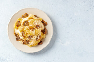 Wall Mural - Pappardelle pasta with mushrooms, cream sauce and grated Parmesan cheese, shot from the top with copy space