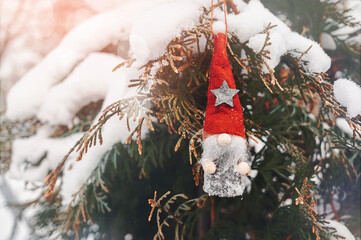 small figure of Santa in a red hat with a star is hanging on a Christmas tree