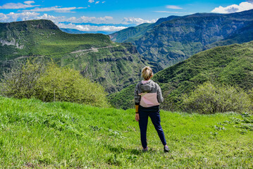 A girl on the background of a mountain view from the territory of the Tatev monastery, an Armenian Apostolic monastery of the 9th century, Armenia. May 5, 2019.