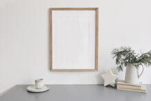 Christmas Still Life. Blank Wooden Picture Frame Mockup. Cup Of Coffee, Pine Tree Branches In Jug On Grey Table. Old Books And Ceramic White Star Decor. Scandinavian Festive Poster Winter Home Decor.