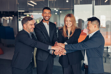 Happy group of multi ethnic coworkers stacked hands together as concept of corporate unity