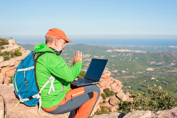 mature man sitting on top using laptop to make video call, digital nomad concept