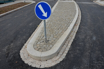 roundabout of paving of gray granite cubes in a rolled sill closer to the center. beveled concrete curbs, a transport hub, with flowers and grasses in the middle of the circle. perennial flowerbed 