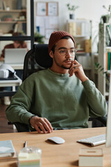 Leinwandbilder - Young modern IT engineer sitting by workplace in front of computer and looking at screen while starting new program for decoding information