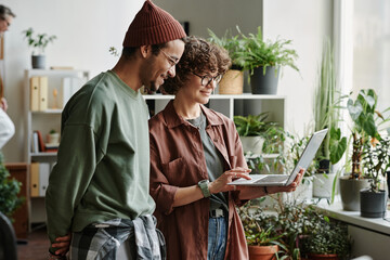 Poster - Two young software developers discussing online information and their ideas while creating new program with help of online advice
