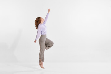 Wall Mural - Portrait of young woman reaching top isolated over white studio background. Growing professional ambitions