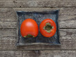 Persimmon fruits on a blue ceramic tray on a wooden background. Top view. Photo directly from above.
