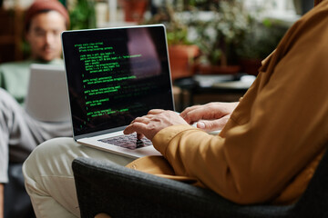 Leinwandbilder - Mature professional IT engineer developing new software or decoding data on laptop scren while typing in front of young coworker