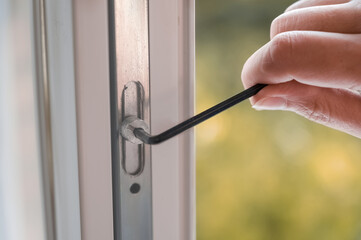 handyman adjusts the pvc window in the room. a worker uses a hexagon to repair a pvc window.