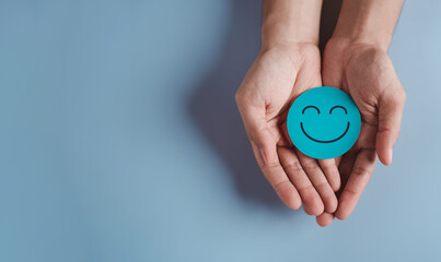 hands holding blue happy smile face, good feedback rating, positive customer review, experience, sat