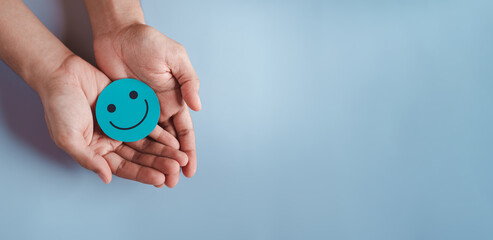 Hands holding blue happy smile face, good feedback rating, positive customer review, experience, satisfaction survey, smiley mental health, child wellness, world mental health day on blue background