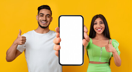 Poster - Mobile Mockup. Middle Eastern Couple Demonstrating Blank Smartphone And Showing Thumbs Up