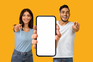 Poster - Cheerful Arab Man And Woman Showing Blank Smartphone And Pointing At Camera