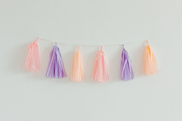 Wall Mural - Tissue paper tassel garland. Pastel colors on the white background. Decoration for party. Minimalist style, copy space
