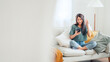 © oatawa - Happy asian woman listening to music from mobile phone while sitting on the the sofa at homes, Smiling girl relaxing with headphones in morning, Time to relax. copy space.