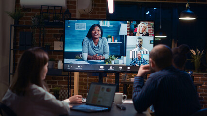 Wall Mural - Employees planning strategy with remote team in teleconference app, coworkers brainstorming videoconference. Diverse office workers listening to presentation in online business meeting. Handheld shot.