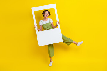 Full length photo of attractive funky cheerful lady dancing holding frame have fun enjoy isolated on bright yellow color background