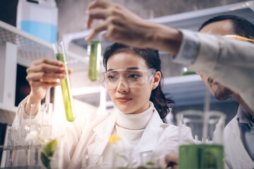 Wall Mural - Two research people are comparing and discuss information about substance with tube in their hands at cosmetic lab. They are happy in their research.