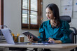 © David - Attractive smiling young asian business woman work at home office, Asian woman working on laptop computer holding tablet.