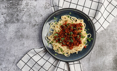 Wall Mural - Traditional italian pasta bolognese with beef and tomato sauce  on a round plate on a dark gray background. Top view, flat lay