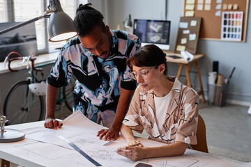 Wall Mural - Portrait of two creative young people working on interior design project in office with dim lighting, copy space