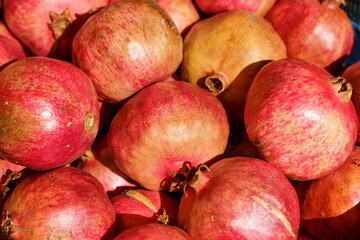 Wall Mural - Juicy ripe pomegranate fruits on the market counter for juice. Pomegranate harvest on agricultural farm, vitamins, fruits, tropics concept.