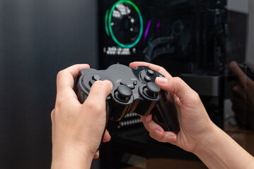 Fototapete - Gamepad in hand with modern gaming PC case in background. PC gaming concept