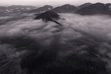 Fototapeta Las - A panoramic view from above of the mountain peaks in thick clouds.