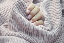 Female hands with beautiful nails, pink manicure close-up on the background of a pink knitted sweater. Shellac, gel polish.